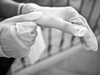 Two hands putting on white gloves