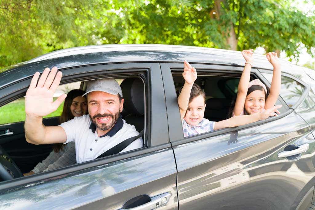 Image of a family waiving goodbye while driving off