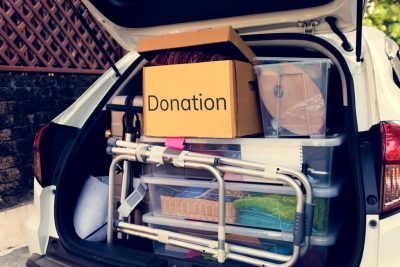 Image of the back side of a car hatchback filled with storage boxes and items for donation