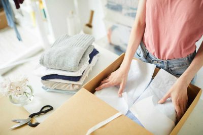 Image of a woman packing winter clothes away in a box