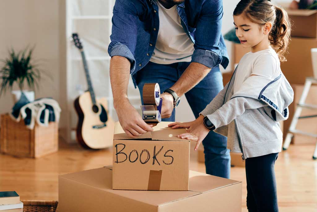 Image of a father helping his daughter pack books into a box